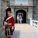 Guard at the Citadel in Halifax, Nova Scotia unaware of approaching American tourists, Julia and Sam