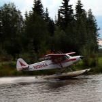 Plane takes off alongside paddlewheel riverboat