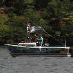 Infamous "Ship of Fools" sailboat with dangling skeleton on top of motorized platform boat cruising on Lake Burton 