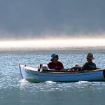 Unknown couple with white dog cruise the lake in a boat named "Charger" as the sun rises