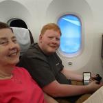 Sam and Julia enjoying comfortable economy class seats in Korean Air 787 with windows that can be darkened to allow such a photo even showing the view outside the plane, note button under window