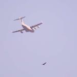 Boeing C-17 Globemaster military transport plane flying above Georgia State Stadium and a lone bird