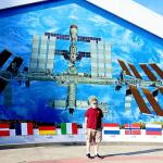 Sam in front of outdoor mural of International Space Station at Kennedy Space Center Visitor Complex