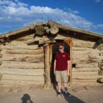 Sam at front door of Wolfe ranch cabin at Arches NP near Moab